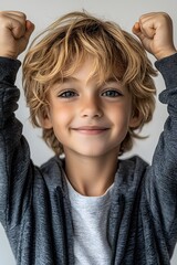 joyful child with curly hair celebrating with raised arms in casual attire