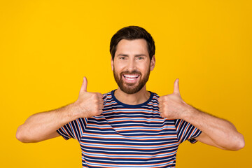 Wall Mural - Portrait of optimistic positive guy with stylish bristle wear striped t-shirt showing thumbs up isolated on yellow color background