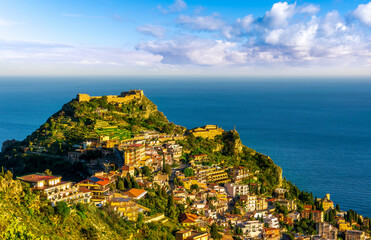 scenic view at beautiful mountain town on a sea coast in Italy with green hills, antique buildings and amazing blue sea on backgeound of landscape