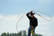 © Connect Images - Cowboy performing a lasso trick under a cloudy sky.