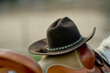 © Connect Images - A close-up photo of a brown cowboy hat with a braided hatband resting on a leather saddle.