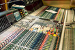 © Connect Images - Close-up view of a professional sound mixing console with various knobs and sliders in a recording studio.
