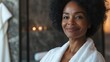 © LoLArt - Georgeous cheerful middle aged african american woman wearing bathrobe at spa salon or hotel relax zone