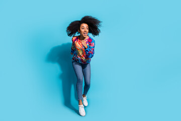 Poster - Full size photo of pretty young girl running look empty space wear trendy colorful outfit isolated on blue color background