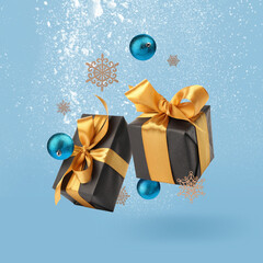 Poster - Gift boxes, Christmas balls and decorative snowflakes in air on light blue background