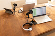 © wavebreak3 - Podcasting setup with laptops, microphones, and headphones on wooden table, copy space