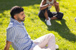 © wavebreak3 - Relaxing on grass, young man enjoying outdoor time with diverse friends