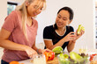 © wavebreak3 - Cooking fresh vegetables, diverse friends preparing meal together in kitchen, smiling and enjoying
