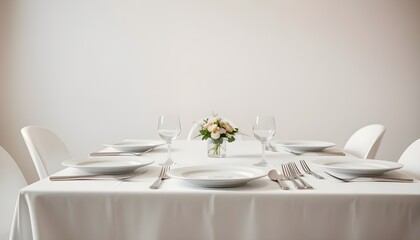 Dining table set with white plates, silver cutlery, and a centerpiece of a small bouquet of flowers.