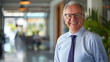 © Mahemud - Executive businessman at the office. Smiling senior investment advisor business man wearing shirt and tie while standing at the office and looking at camera