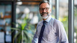 © Mahemud - Executive businessman at the office. Smiling senior investment advisor business man wearing shirt and tie while standing at the office and looking at camera