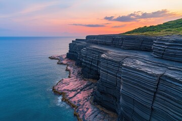 Wall Mural - Layered coastal cliffs at sunset with calm waters lapping at the shore. The stratified rock formations stand against a colorful sky, creating a tranquil and scenic landscape.