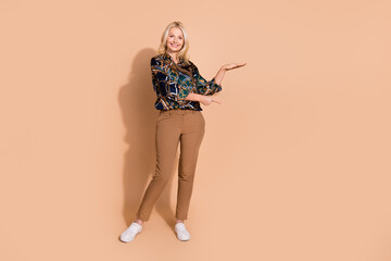 Poster - Photo of blonde hair happy mature business lady in glamour shirt pointing finger measure height isolated on beige color background