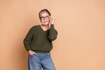 Poster - Photo of smart woman with short hairdo dressed khaki sweater touch glasses look at sale empty space isolated on beige color background