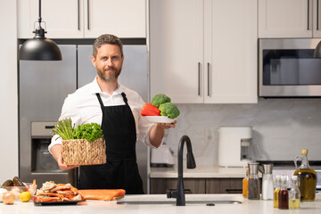 Home menu with fresh food ingredient. Man cook cooking at kitchen. Hispanic man smiling in kitchen preparing food. Millennial man cook healthy salad. Food diet. Man cook a tasty meal