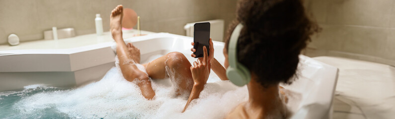 A woman bathes while using her phone, barefoot and barechested