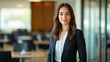 © Michael - Young businesswoman is posing in a modern office building, wearing a suit and smiling