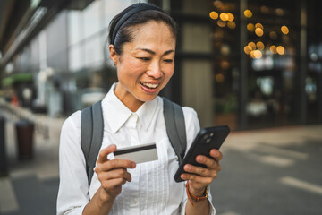 japanese woman buy online on cellphone with credit card outdoor