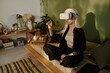 © AnnaStills - High angle of young woman with albinism wearing headset sitting on couch with legs crossed using virtual reality app