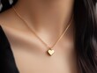 © Spencer - Gold heart-shaped pendant necklace worn on a woman's neck.
