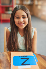 Poster - Girl, child and portrait in library with books, happy and alphabet for education, development and progress. Kid, smile and folder for notes, language and scholarship for studying at school in Mexico
