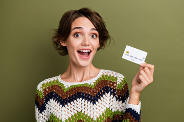 Canvas Print - Photo of funny impressed girl dressed striped clothes holding credit bank isolated green color background