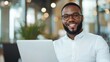 © top images - A man with glasses is smiling and holding a laptop