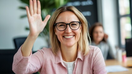 A woman wearing glasses is smiling and waving at the camera