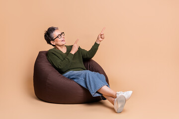 Photo of charming adorable woman wear khaki stylish clothes sit soft bag recommend empty space isolated on beige color background