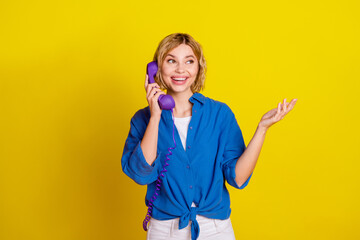 Poster - Portrait of pretty young lady speak cable phone wear blue shirt isolated on yellow color background