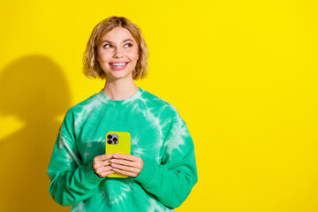 Sticker - Photo of shiny thoughtful lady dressed tie dye sweatshirt communicating modern gadget looking empty space isolated yellow color background