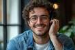 © Art_You - A handsome young man with curly hair and glasses smiling while talking on the phone in a relaxed casual setting