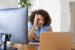 © Wavebreak Media - Working from home, woman with curly hair looking frustrated at laptop and desktop monitor