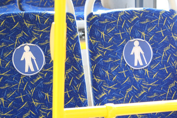 Poster - A single bus seat with a blue and yellow seat cover, ideal for travel or transportation scenes