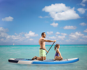 Poster - Man paddling a SUP board with a little girl in the sea