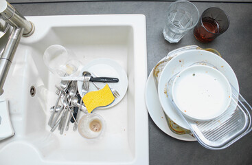 White ceramic kitchen sink full with dirty unwashed dishes 