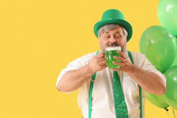 Wall Mural - Mature man in hat drinking beer on yellow background. St. Patrick's Day celebration