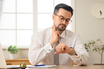 Poster - Young businessman with smartwatch checking his pulse at table in office