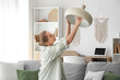 © Pixel-Shot - Young woman screwing light bulb into hanging lamp at home