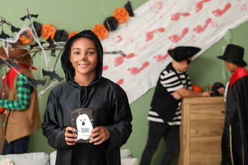 Poster - Cute happy African-American girl dressed for Halloween party with gift box and friends at home