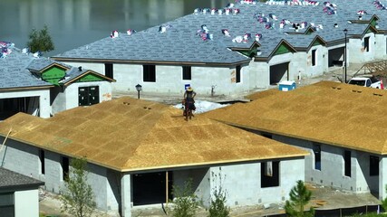 Wall Mural - Aerial view of builders working on unfinished residential house with wooden roof frame structure under construction in Florida suburban area