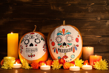 Poster - Pumpkins with painted skulls, burning candles and flowers on wooden background. El Dia de Muertos