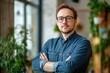 © Dzikrul Husnani - Portrait, glasses and business man with arms crossed in startup office for pride in career or job. Creative, face and confident professional entrepreneur, copywriter and employee coworking , ai