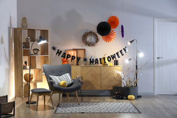 Interior of festive living room with armchair, commode and Halloween decorations in evening