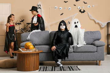 Canvas Print - Teenage boy dressed for Halloween with ghost sitting on sofa at party