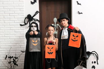 Canvas Print - Kids dressed for Halloween with gift bags at door in hall