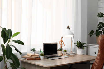 Poster - Workplace with blank laptop, lamp and green plants near window in office