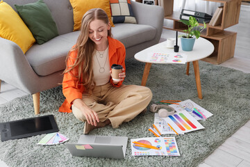 Fototapete - Female web designer with coffee cup working on floor in office