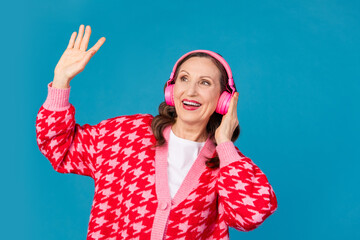 Poster - Photo portrait of attractive retired woman dancing headphones dressed stylish pink print clothes isolated on blue color background