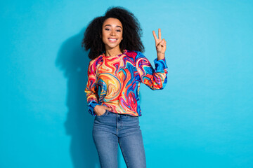 Sticker - Photo portrait of beautiful curly hair happy woman in stylish casual outfit showing v sign posing isolated on blue color background